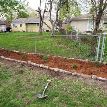a reviewer photo of the yard now with a mulch-filled flower bed 