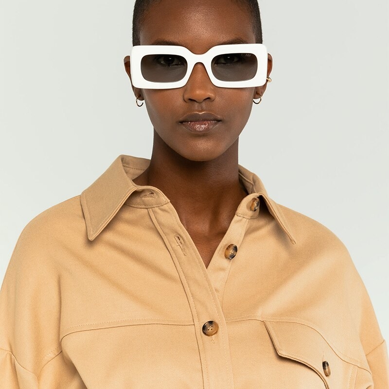 A person wearing a pair of chunky sunglasses while looking into the camera