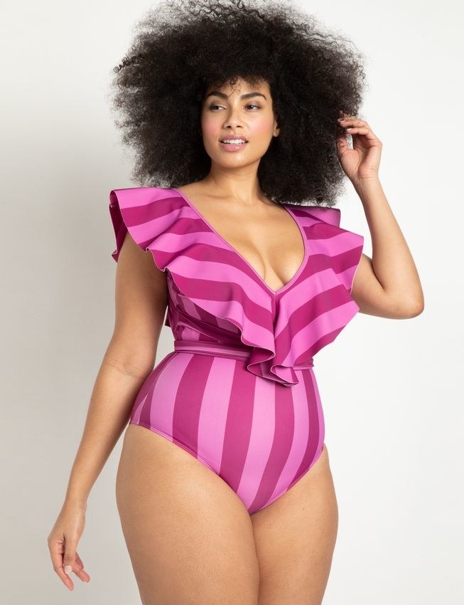 model in pink and magenta striped deep v one-piece with ruffled straps