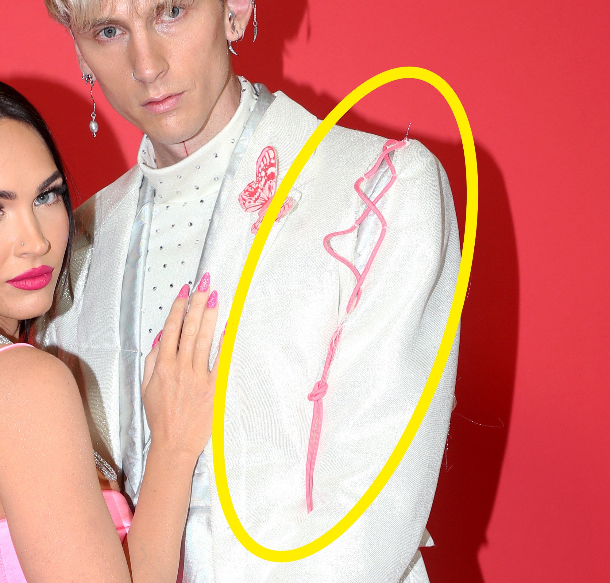 A piece of pink string hangs from the shoulder of his jacket