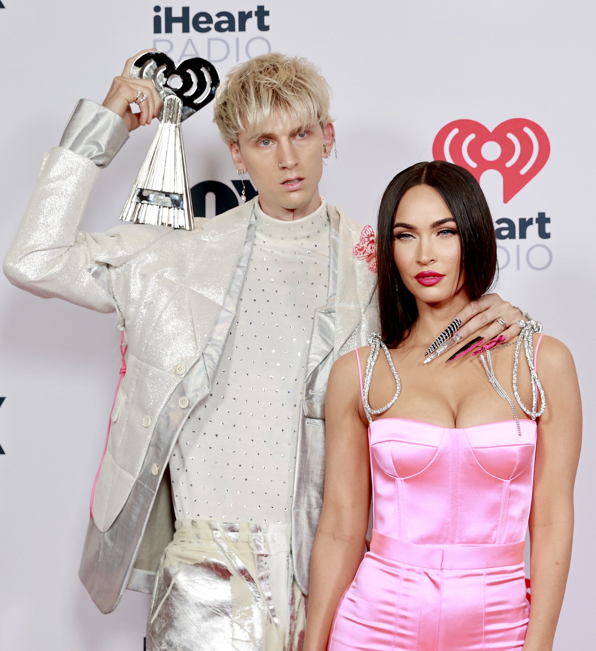 MGK holds up his award on the red carpet 