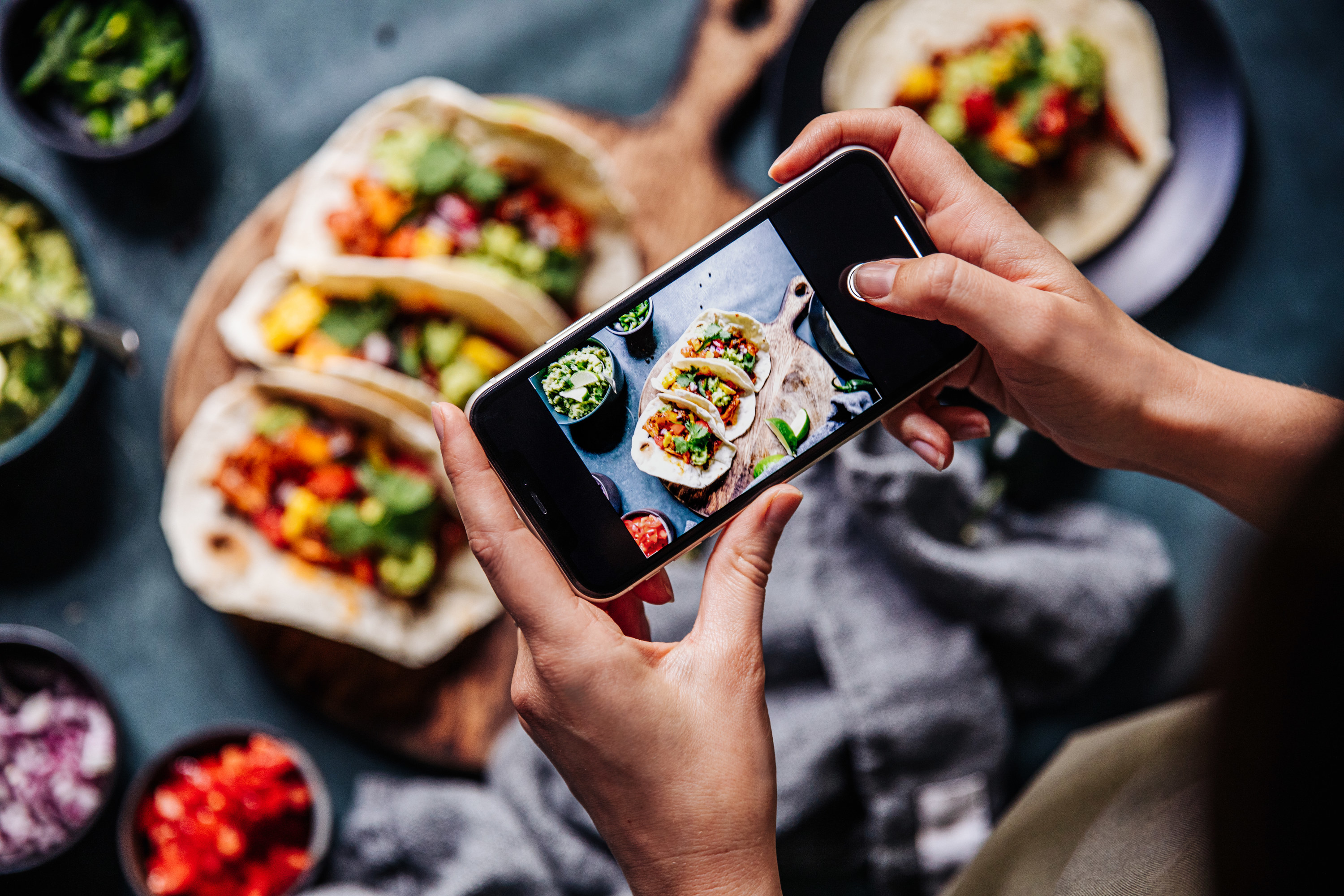 photo of a person taking a photo of tacos from their cell phone