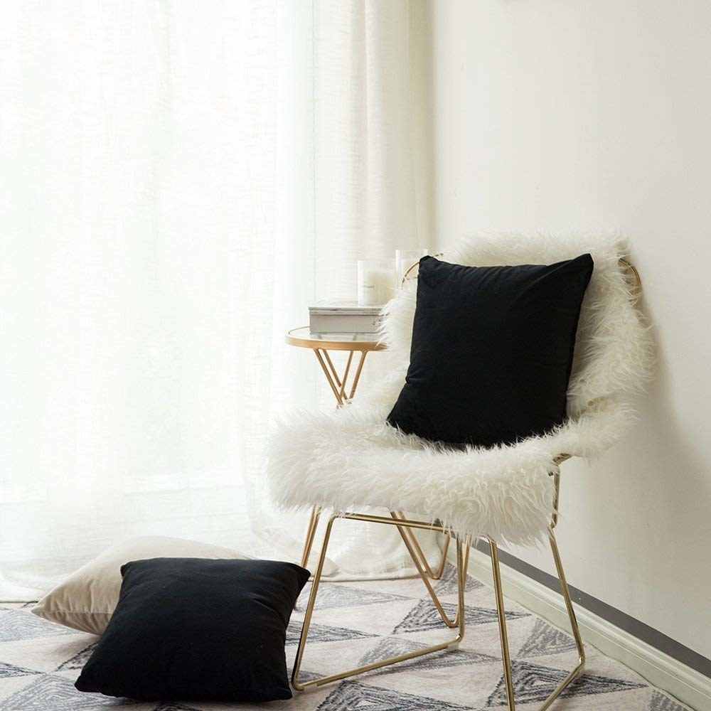 Black velvet cushion on fluffy white chair