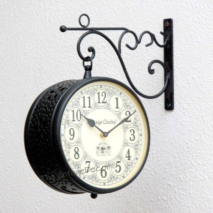 Black iron station clock hanging sideways from wall