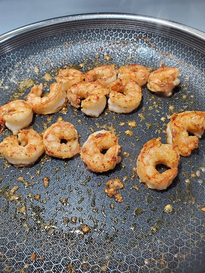A reviewer cooking shrimp in the frying pan