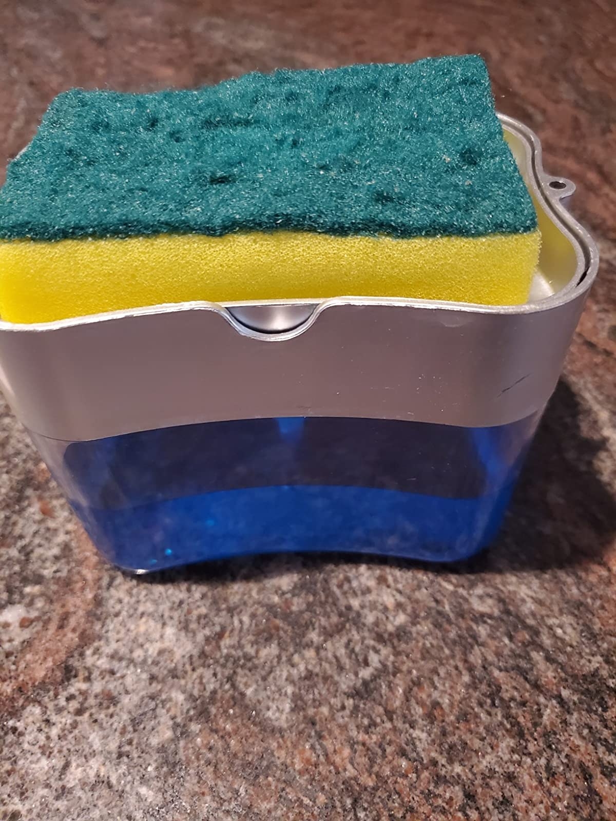 The sponge holder with a sponge resting on top and soap in the bottom half