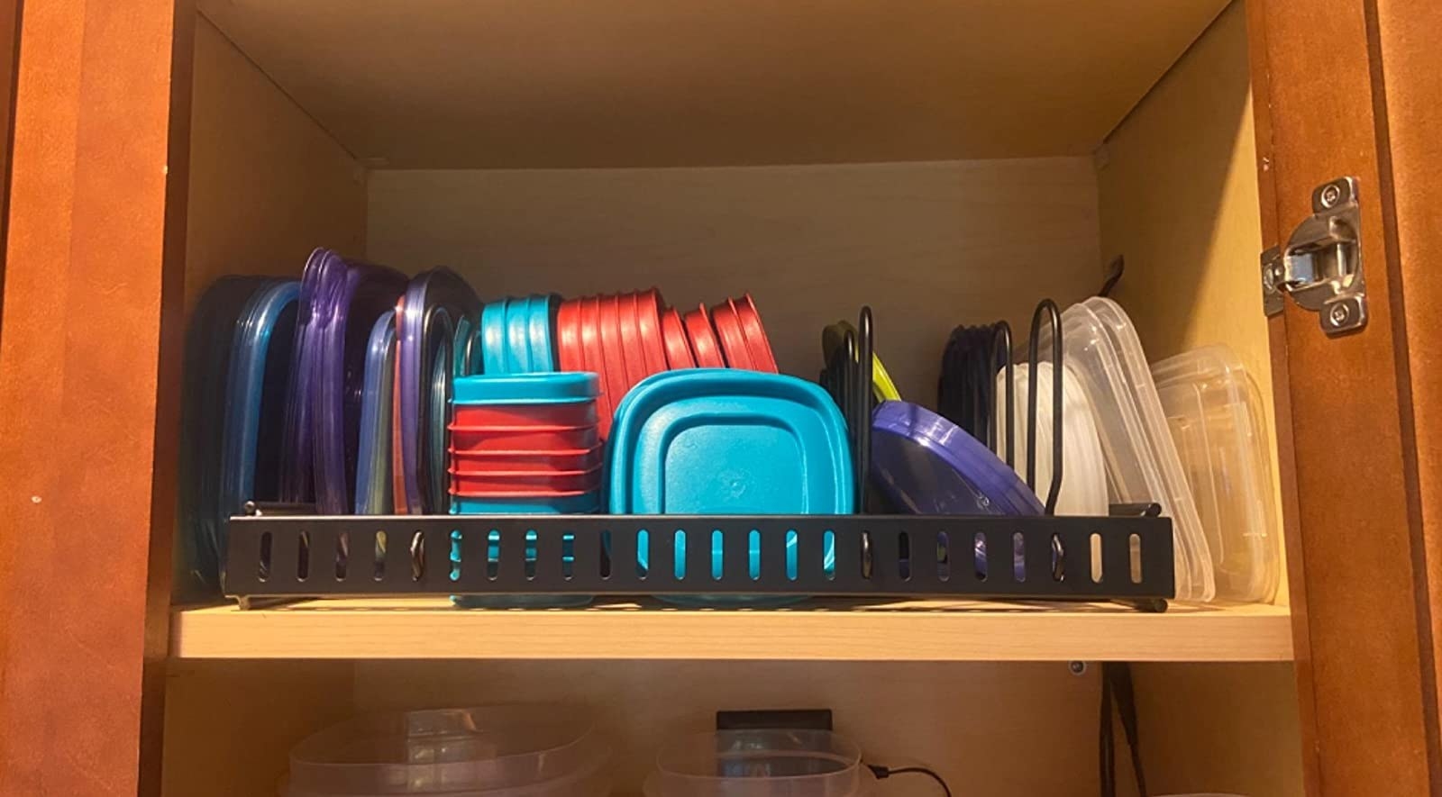 The Tupperware organizer storing several containers and their lids in a cabinet