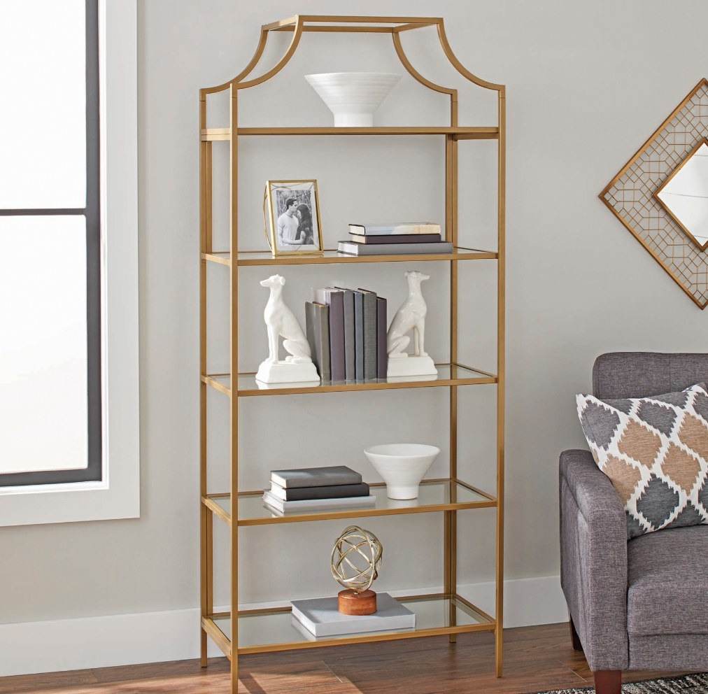 a gold open bookcase with glass shelves