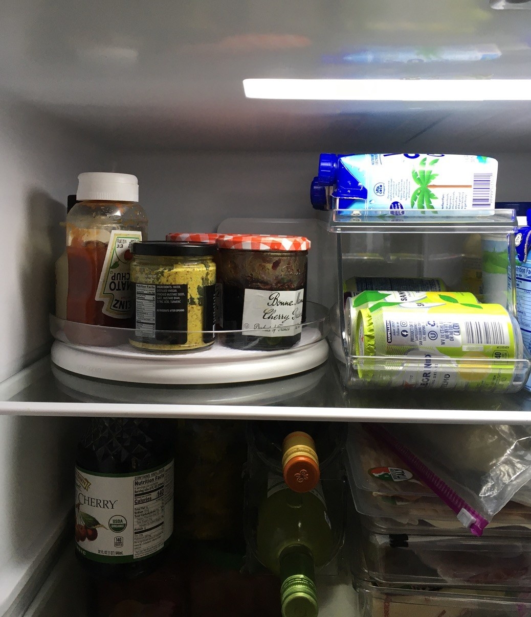 The turntable holding several condiments on the top shelf of a fridge