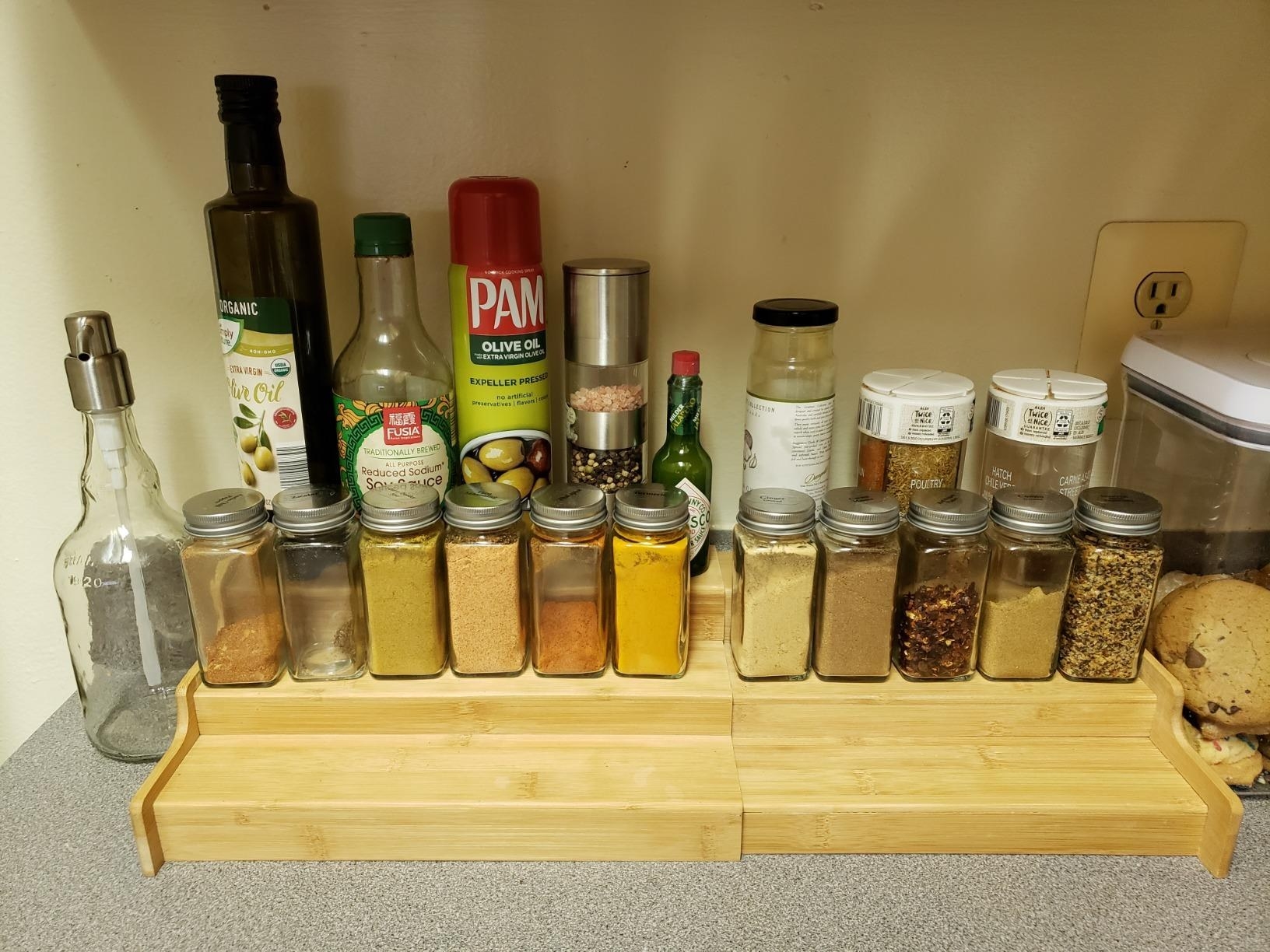 The spice rack holding several spices and sauces on different tiers