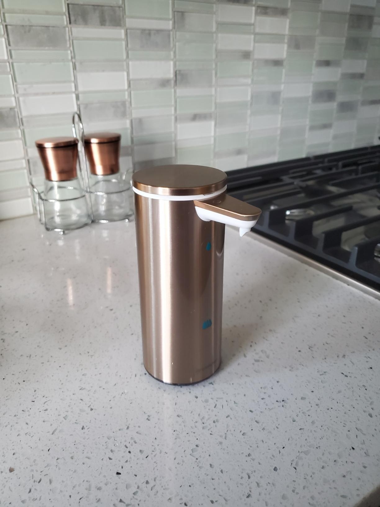 The rose gold soap dispenser on a kitchen counter