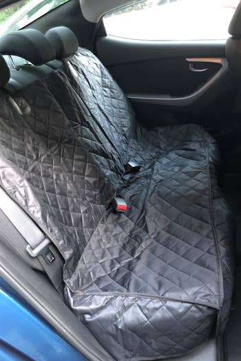 a reviewer photo of the backseat of a car with the quilted cover on it 