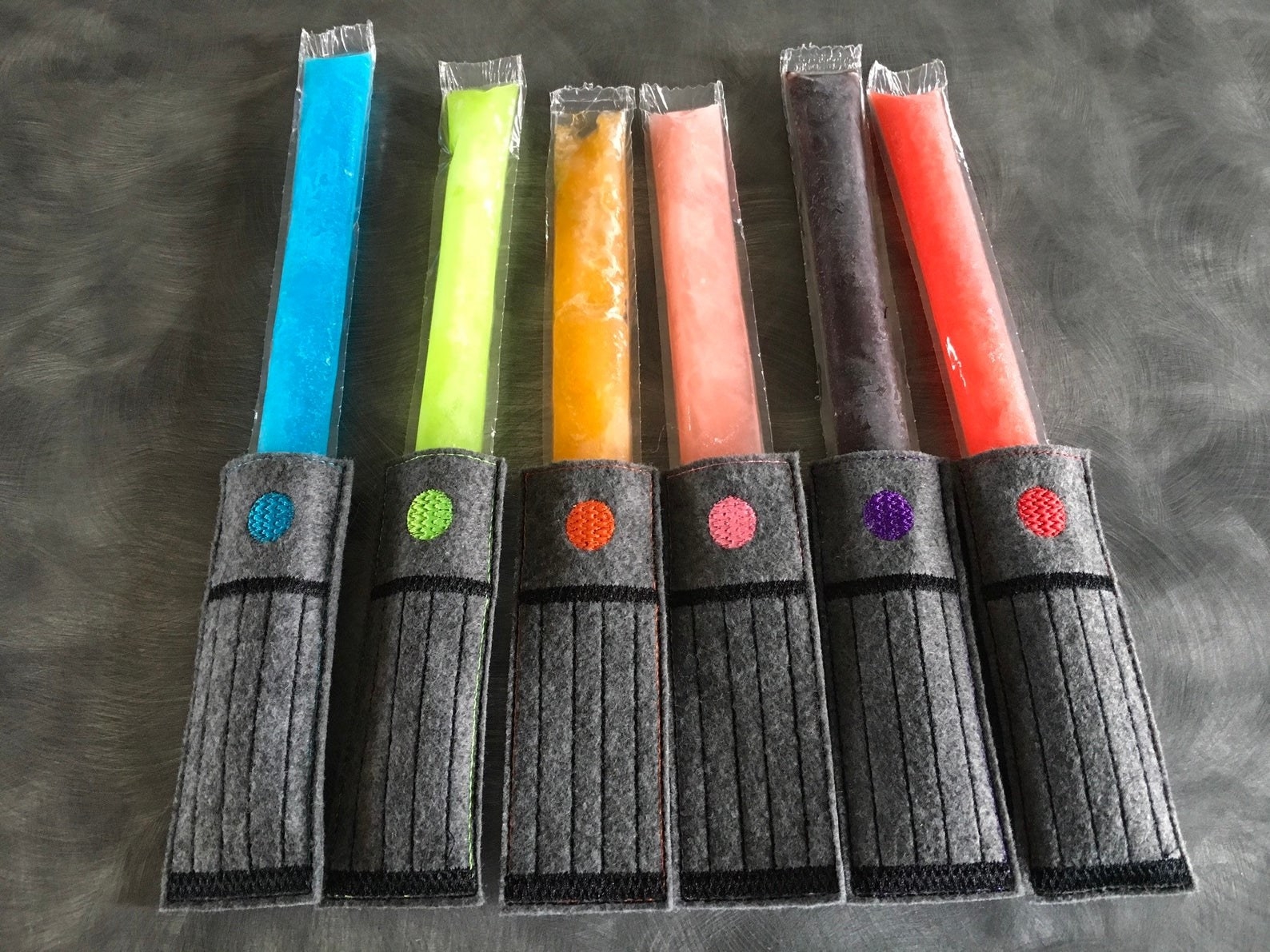 six ice pops with holders on each one that make them look like a lightsaber