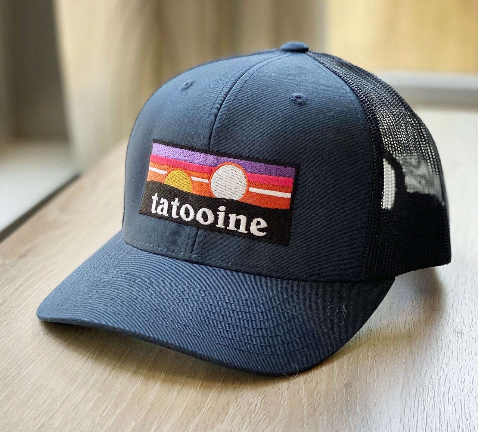 a black trucker hat with a logo of tatooine on it