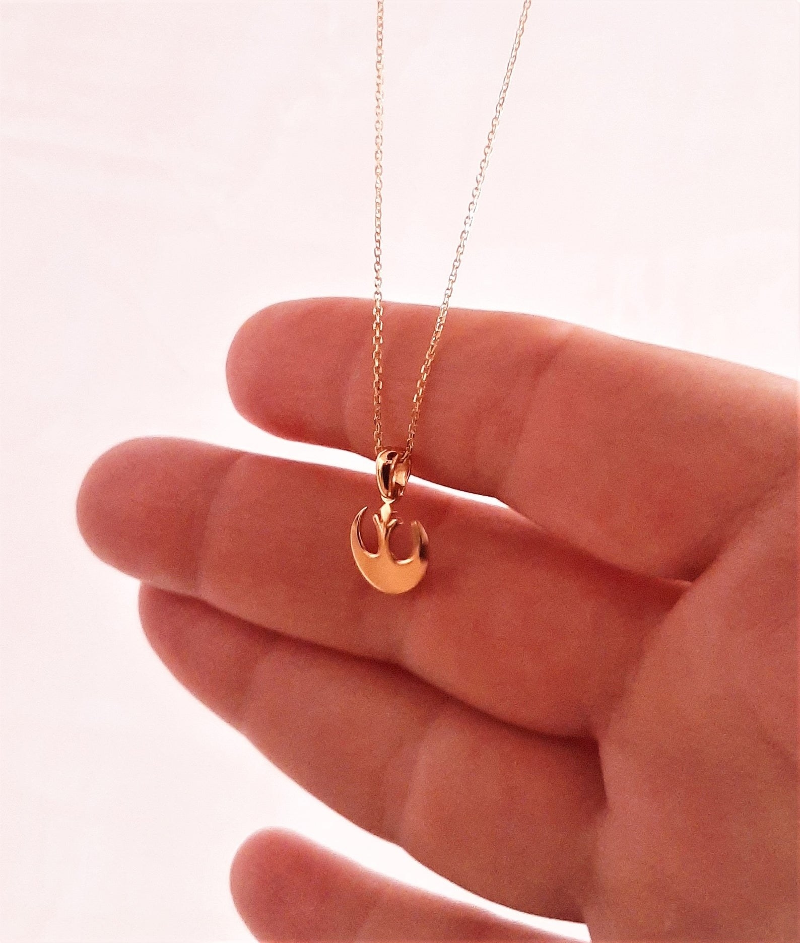 a gold necklace with a rebel alliance pendant hanging from it