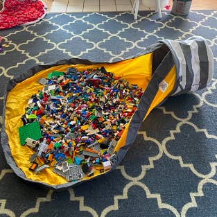 The bag undone with thousands of small toy pieces out on the attached play mat 