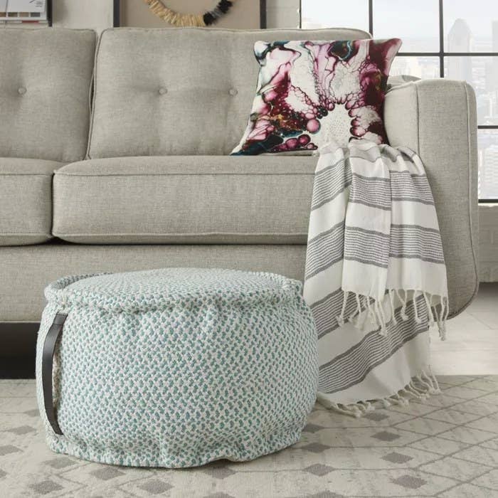 The turquoise pouf with a leather handle