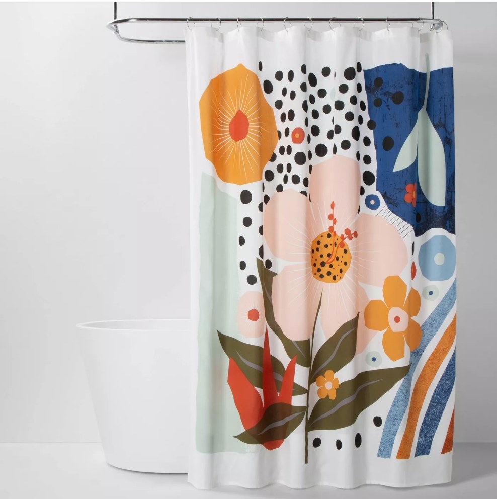 A vibrant, colorful, floral shower curtain hanging on a rod above a bathtub
