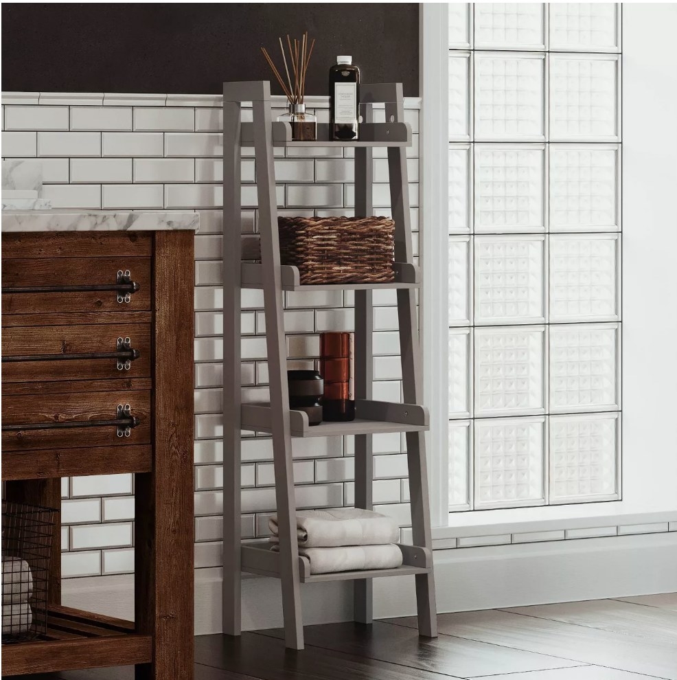 A gray, four-tier, ladder shelf displayed in a bathroom
