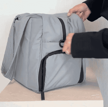 gif of model opening the bag&#x27;s shoe pocket and side phone pocket, and sliding the bag onto a rolling suitcase