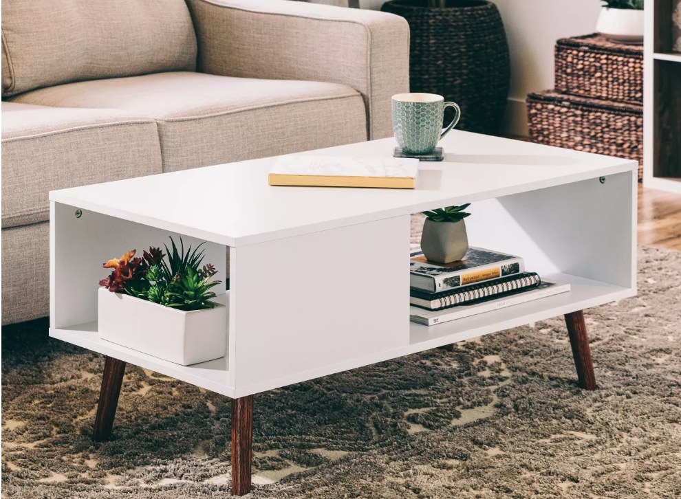 A white, mid-century modern, coffee table with shelving displayed in a living room 