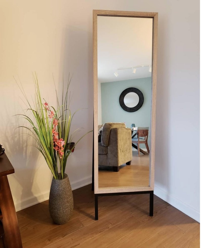 A 20&quot; x 66&quot;, metal and oak standing mirror displayed next to a plant