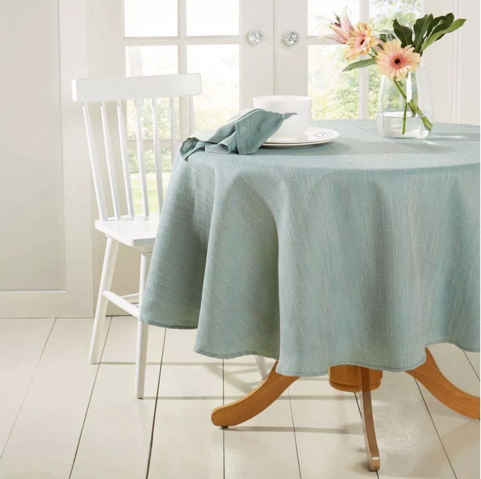 A sea-foam blue, round tablecloth draped over a table 