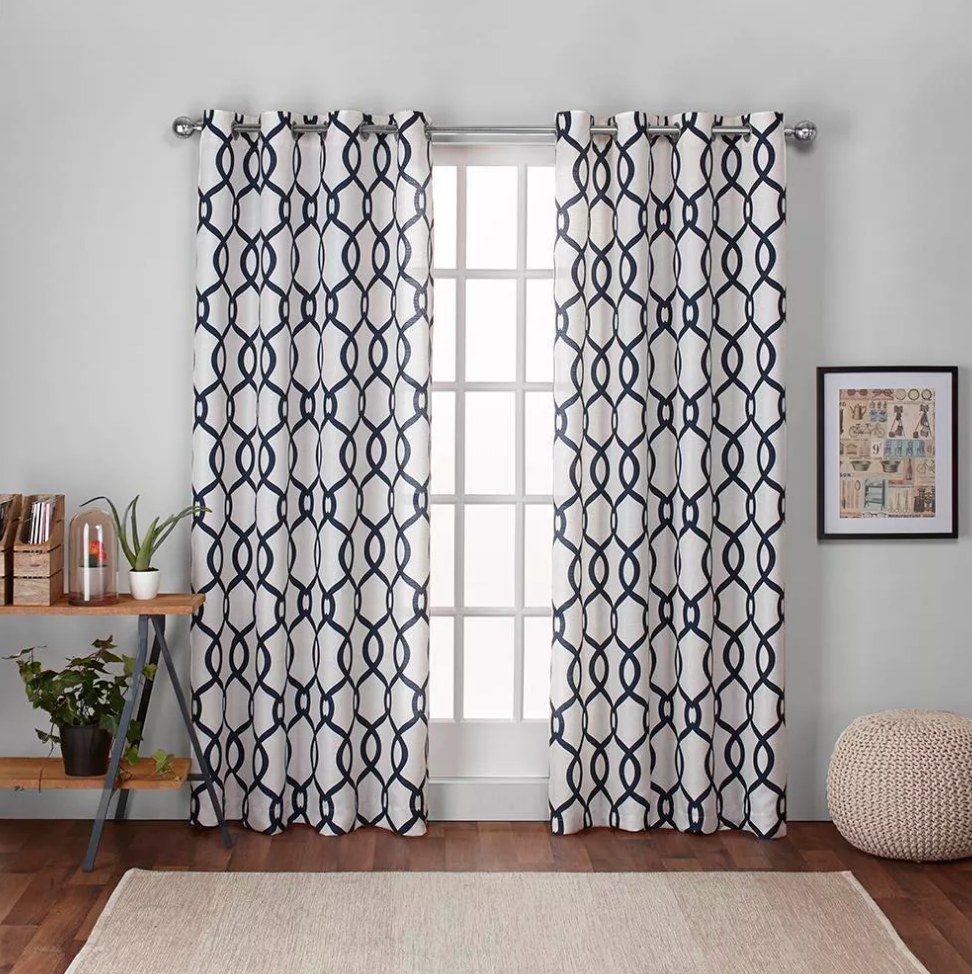 Indigo and white, geometric patterned curtains hanging over a window in a living room