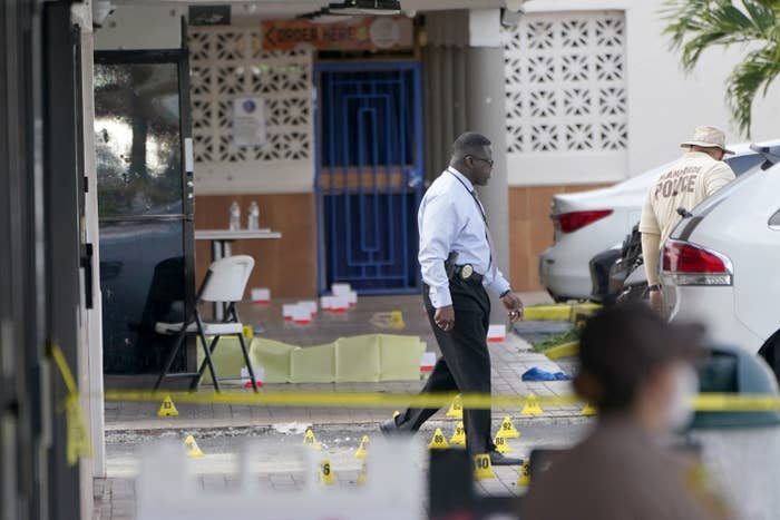 Police walk near a crime scene with yellow markers