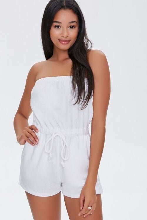 Model wearing white romper with adjustable waist strings, and elastic band around chest area