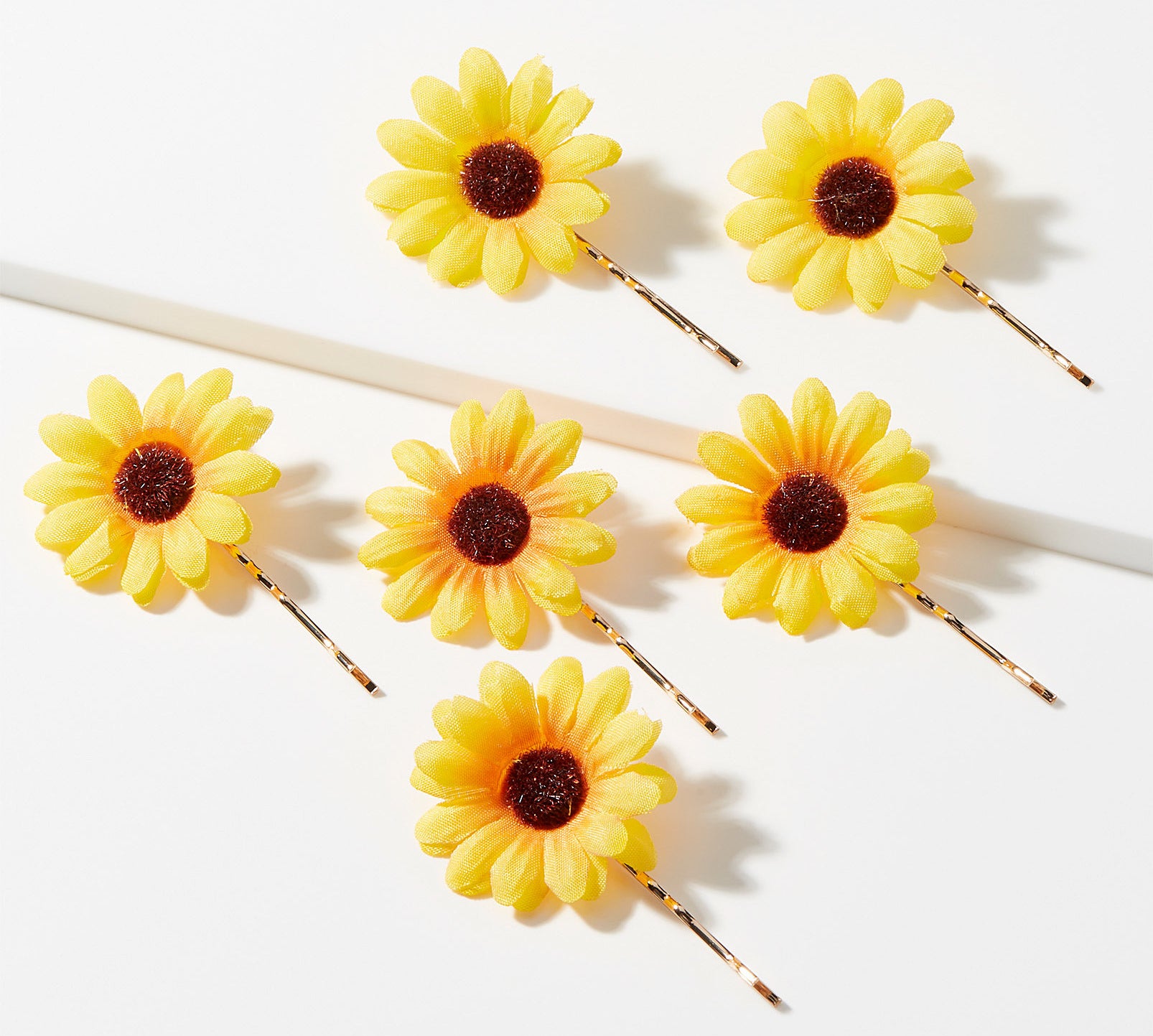 six bobby pins with flowers attached to the ends