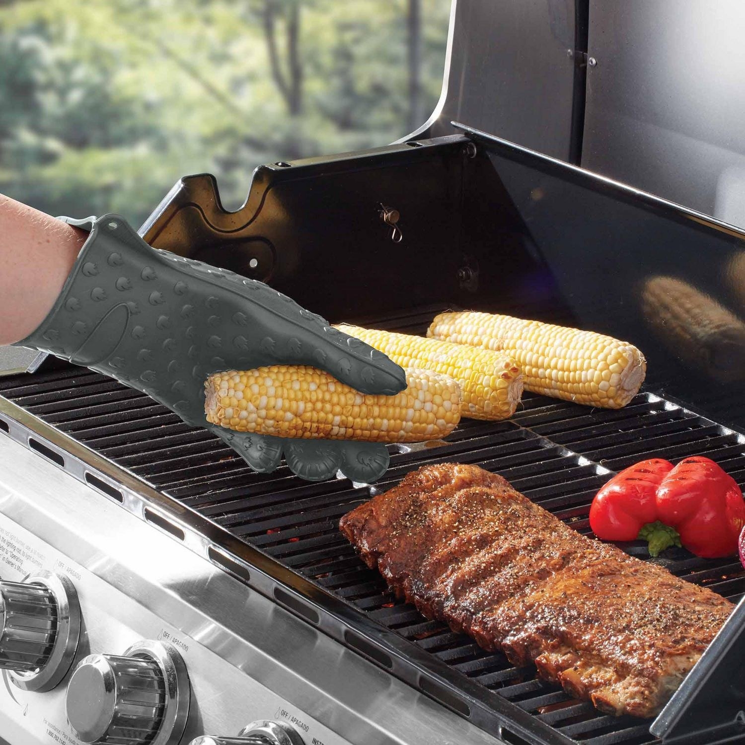A person wearing the gloves while putting corn on a grill