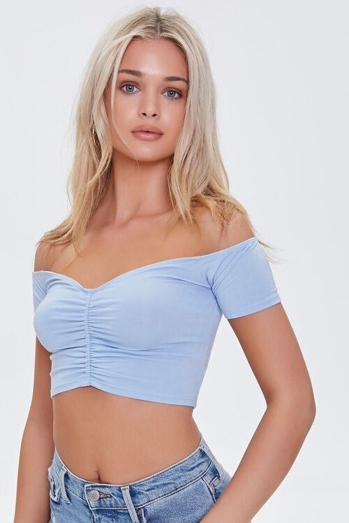 Model wearing blue crop-top with a cinched texture down the middle