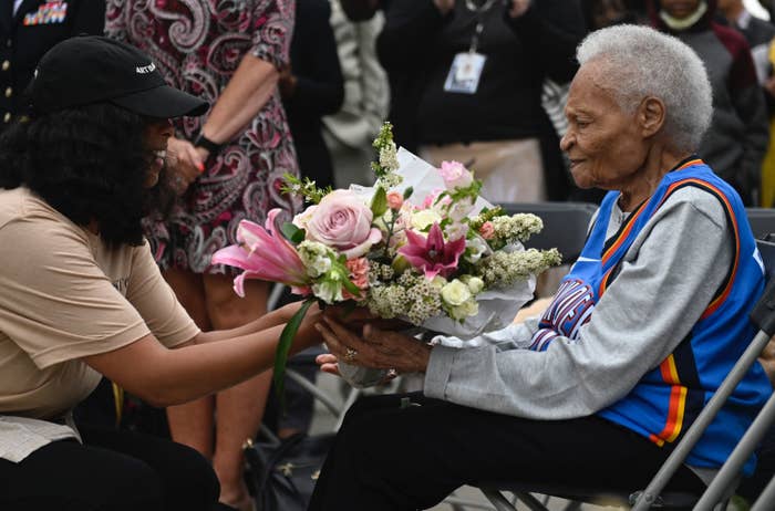 A Black woman in wheelchair receives a bouquet of flowers