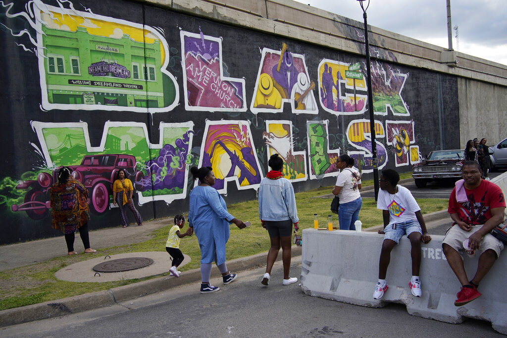 People walk by a colorful &quot;Black Wall St.&quot; mural