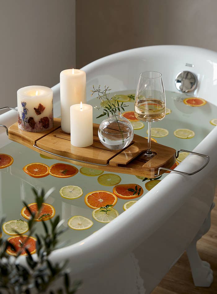 A wooden bath tray sitting across a bathtub filled with water