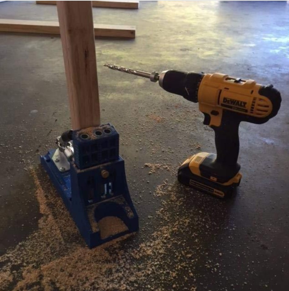 The drill sitting next to wood and other tools while being used for a project
