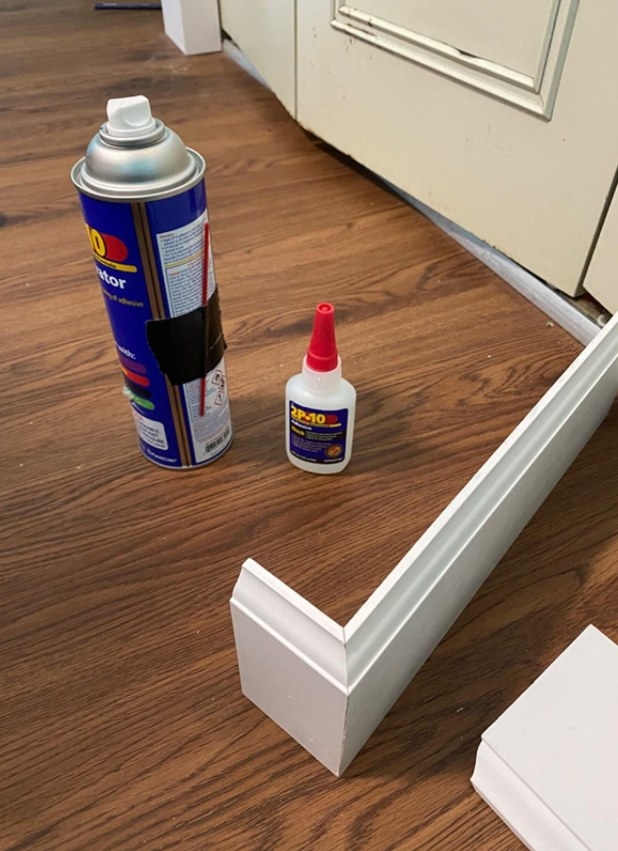 The glue bottle and activator sitting beside two boards of wood that have been glued together