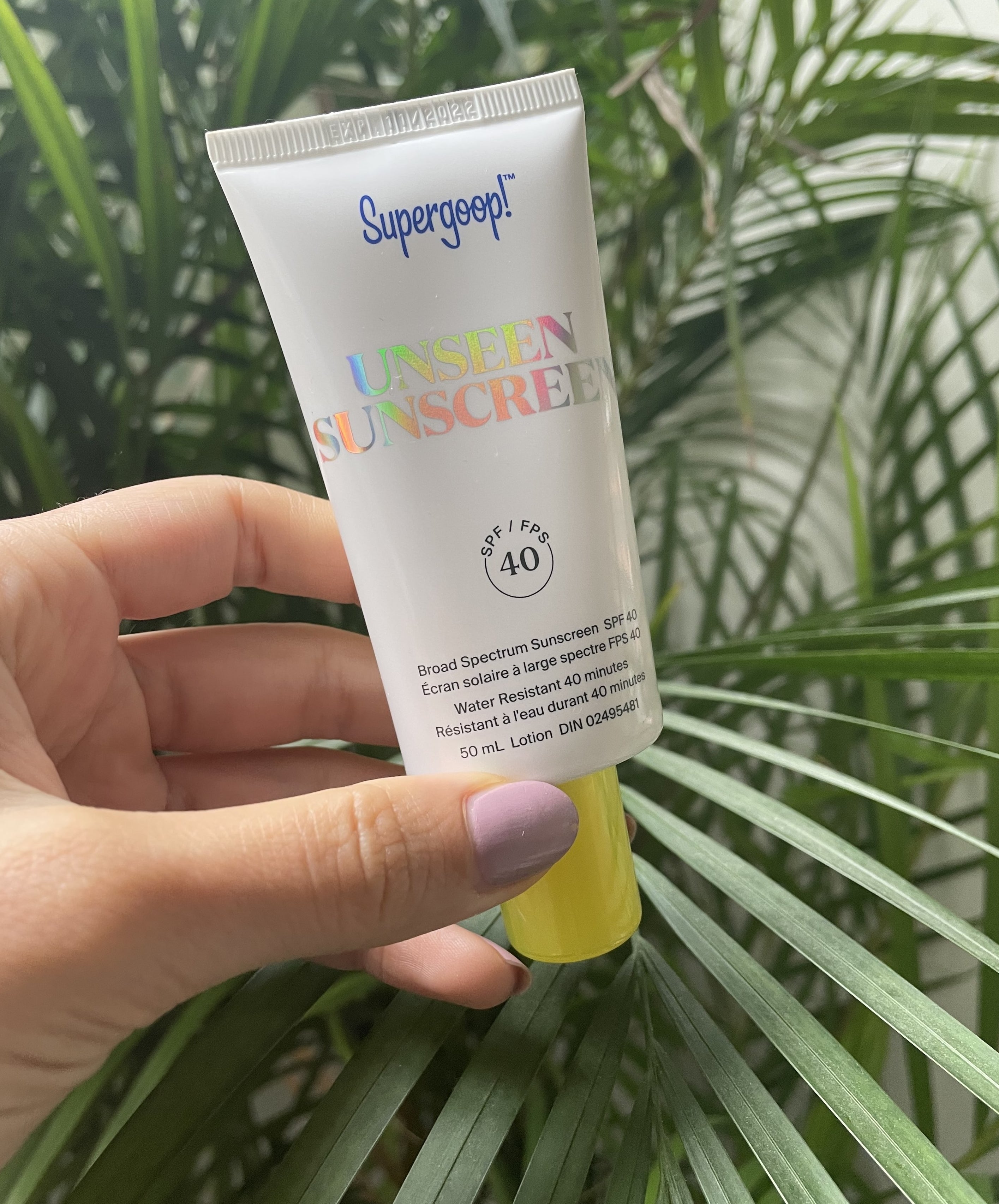Brittany holding up a tube of super goop&#x27;s unseen sunscreen 