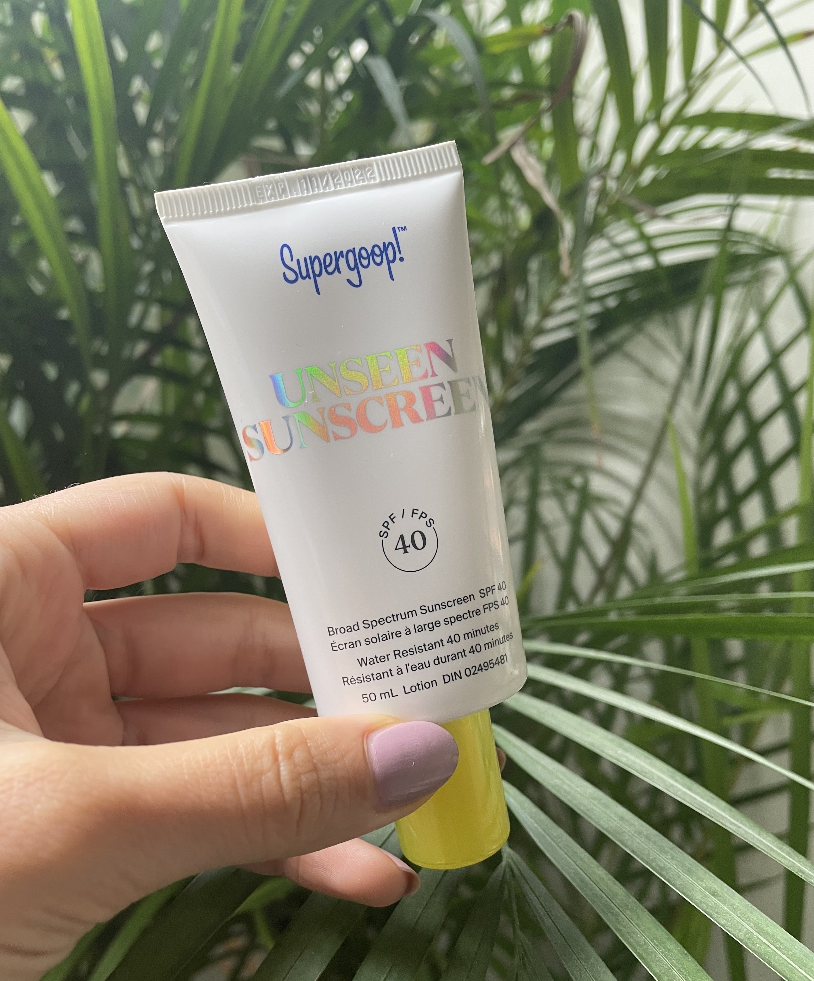 Brittany holding up a tube of super goop's unseen sunscreen