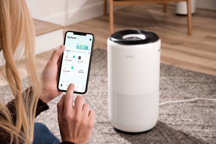 Woman controlling her air purifier on her smart phone