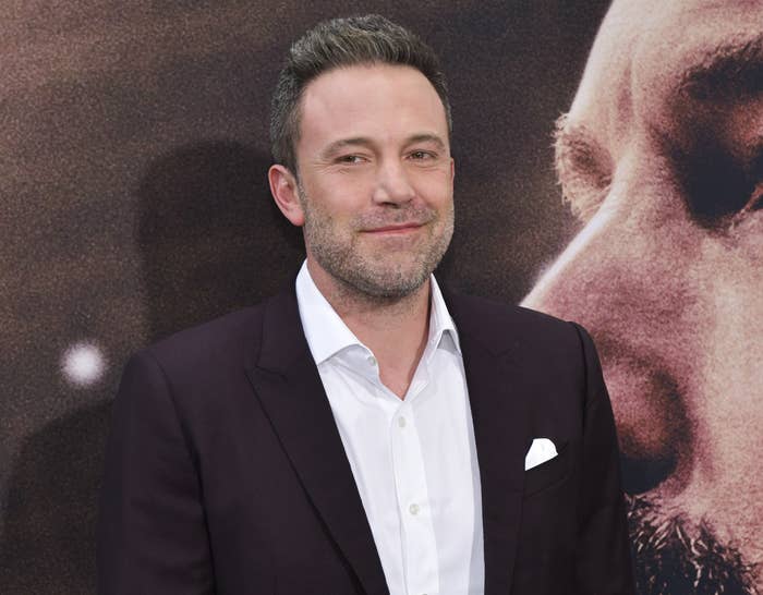 Ben smiles while wearing a suit at a premiere