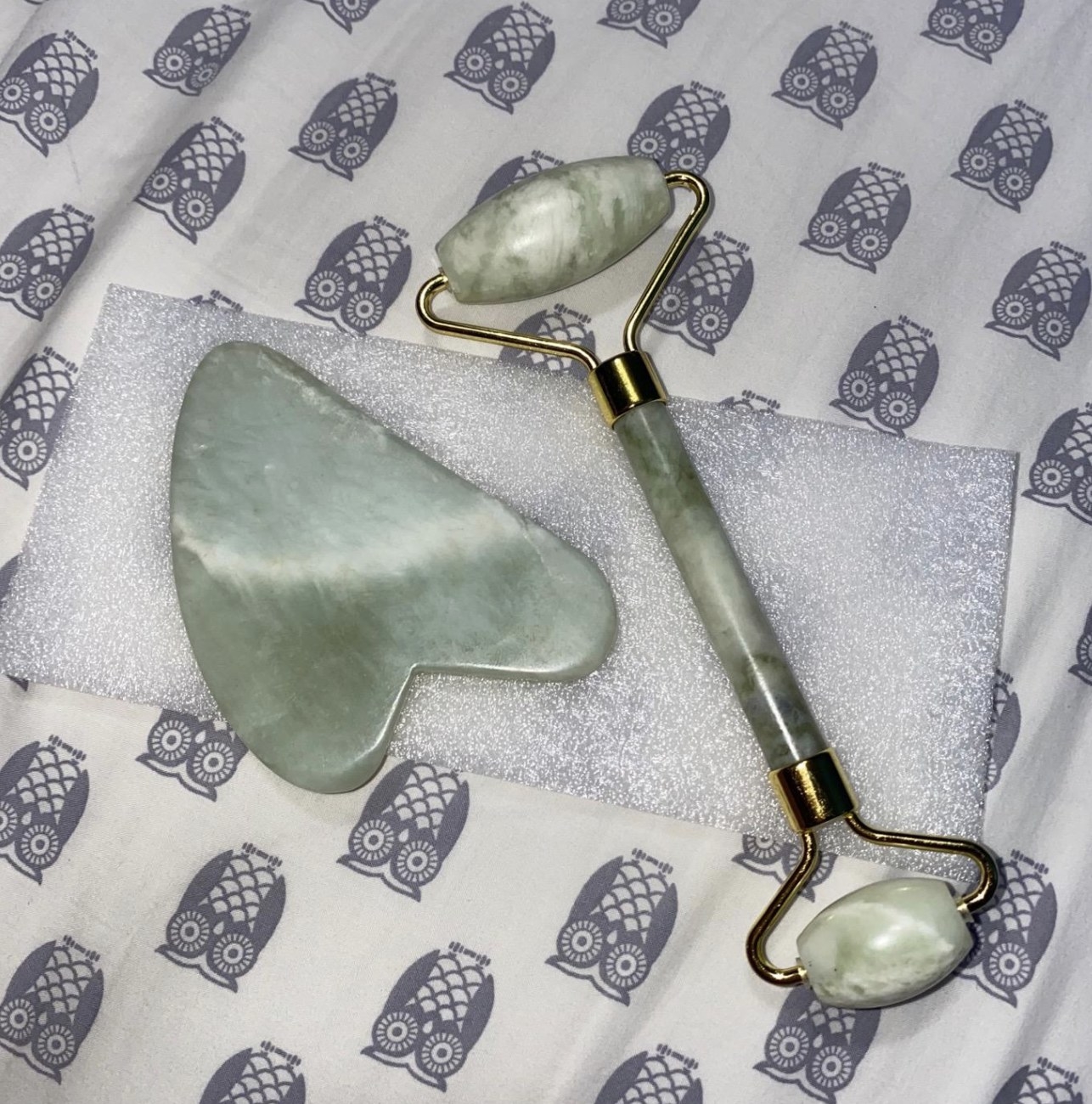 a flatlay of the gua sha tool and double-headed jade roller