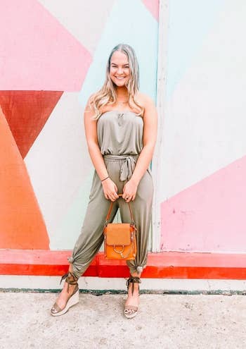 front view of a reviewer wearing the jumpsuit in taupe with the legs tied in a knot