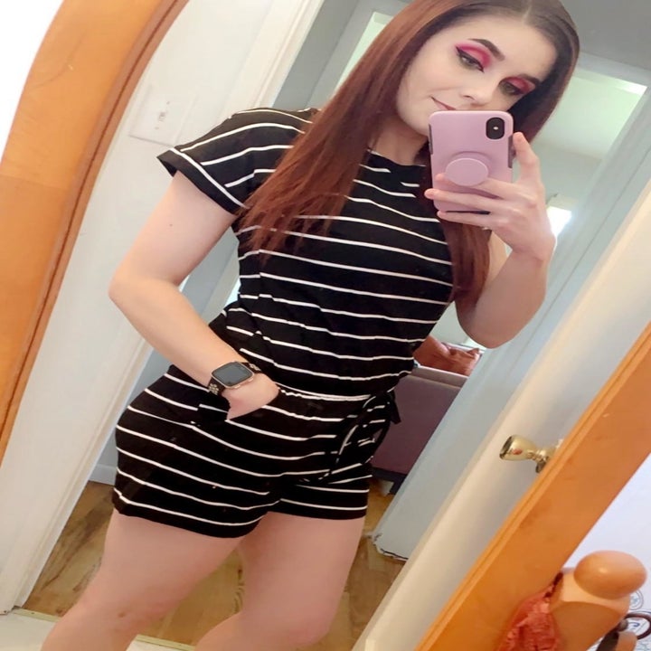 a reviewer mirror selfie wearing the short sleeve romper in a black and white striped print 