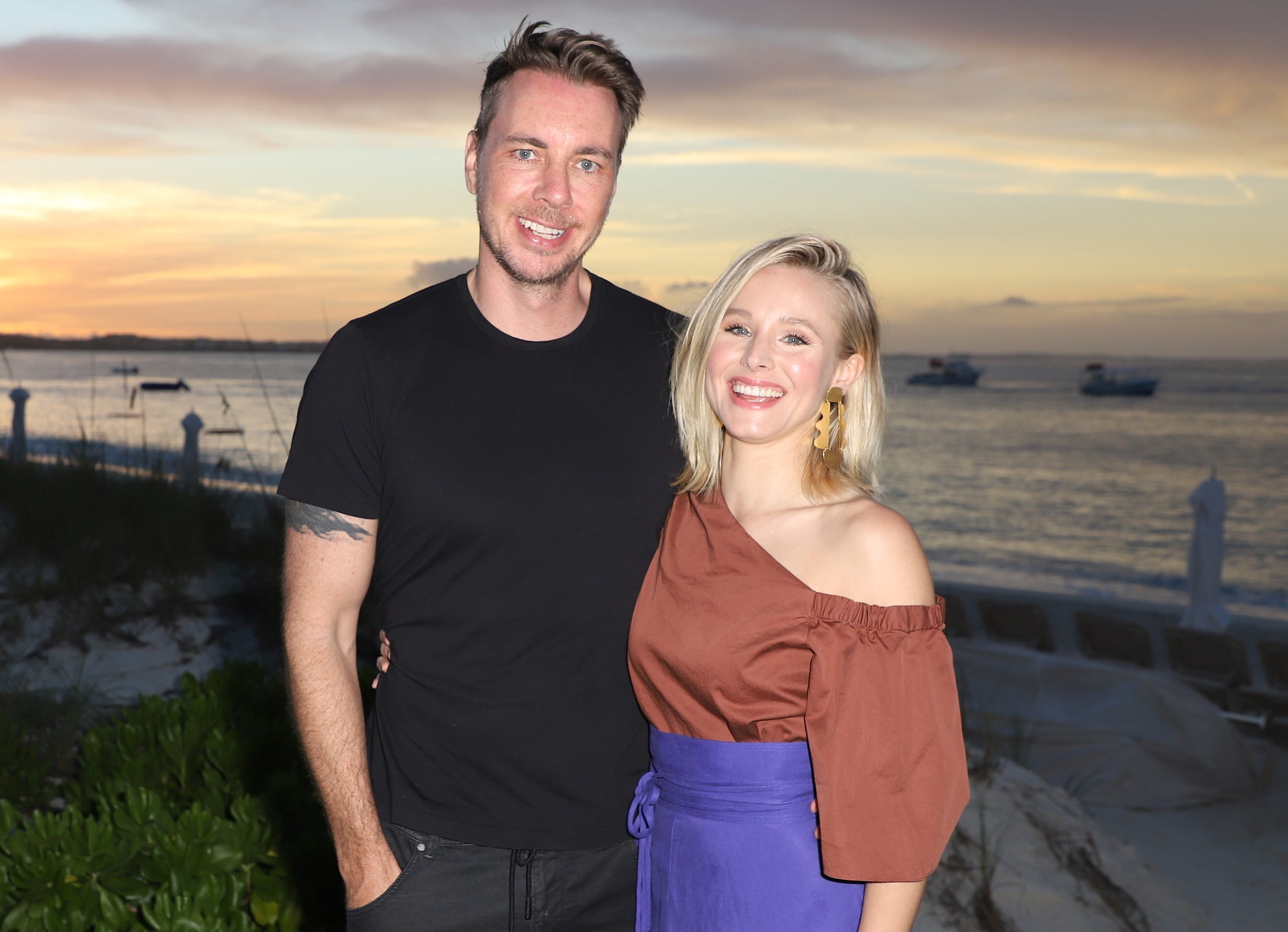 Dax and Kristen smile in front of a beach during sunset