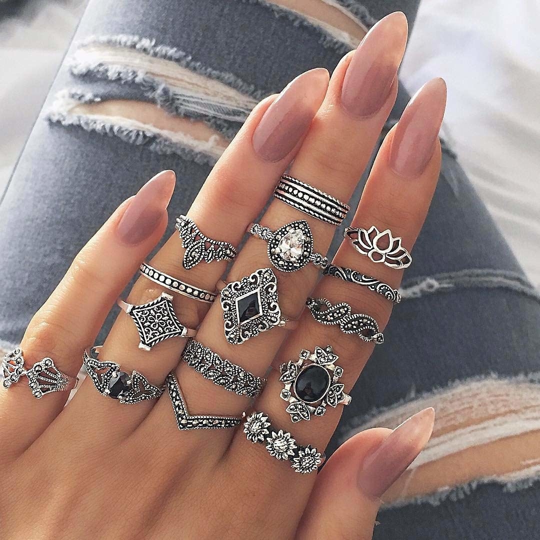 A person wearing oxidised metal rings of varying styles.