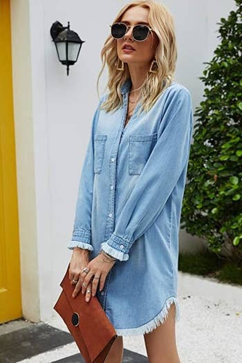 model wearing denim dress in light blue buttoned up with tons of accessories to dress it up
