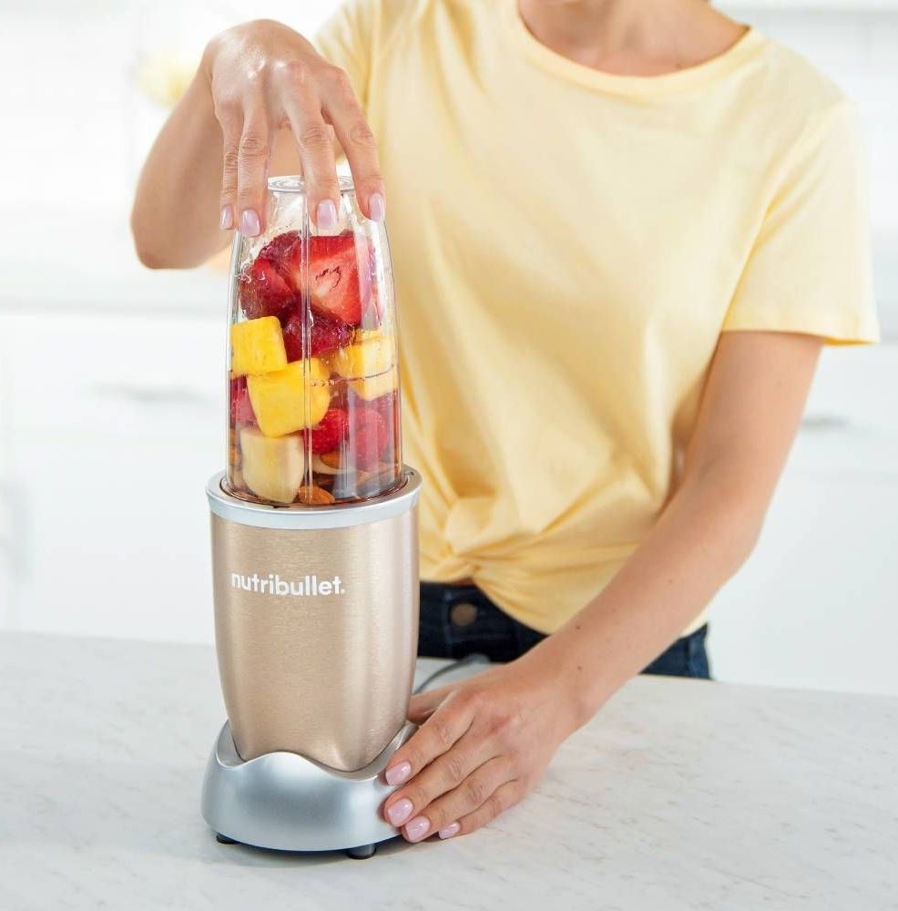 A woman operating a NutriBullet blender in a kitchen