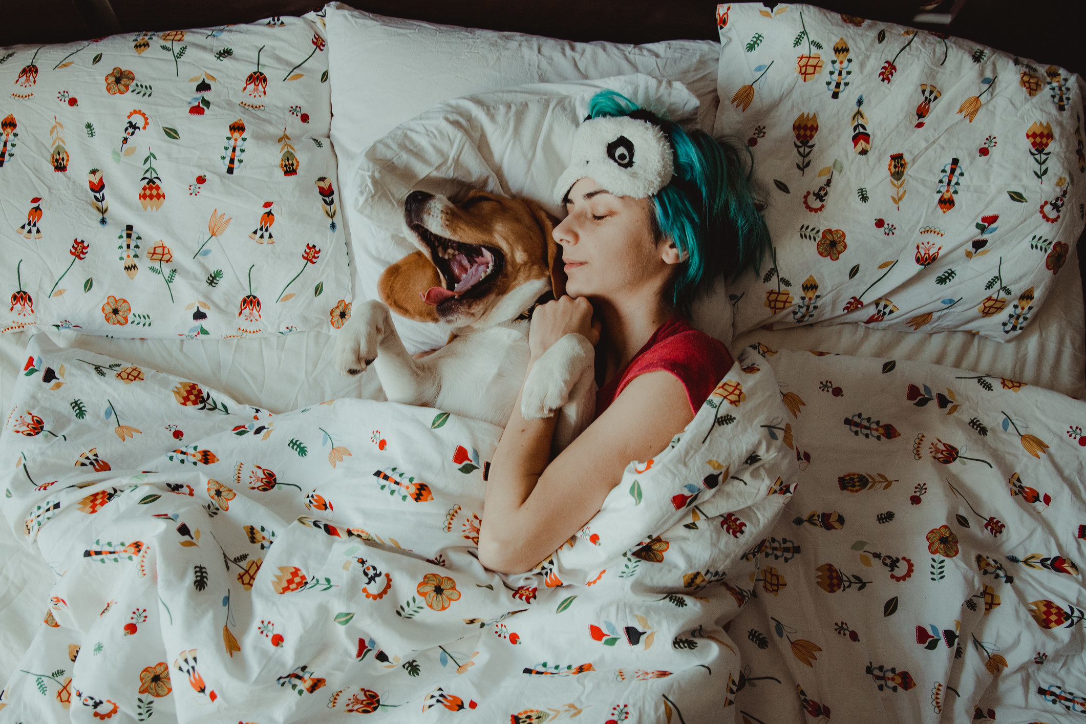 Woman with blue hair asleep with her dog.